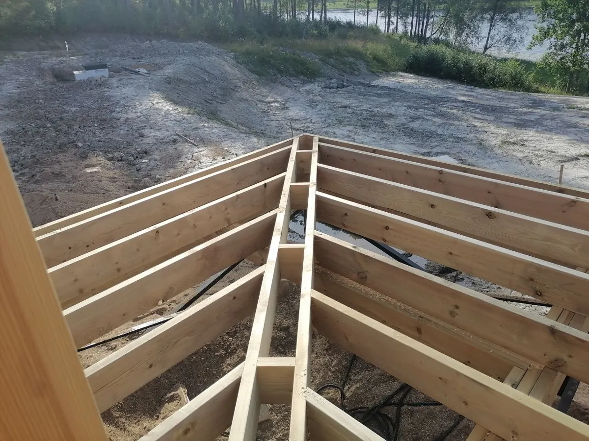 Лаги пола дома на сваях, на заднем плане водоём